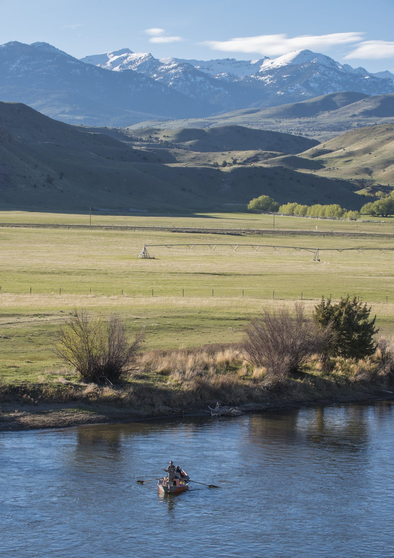 Drift boat floating a wide, scenic reach of the Yellowstone River under a big Montana sky.