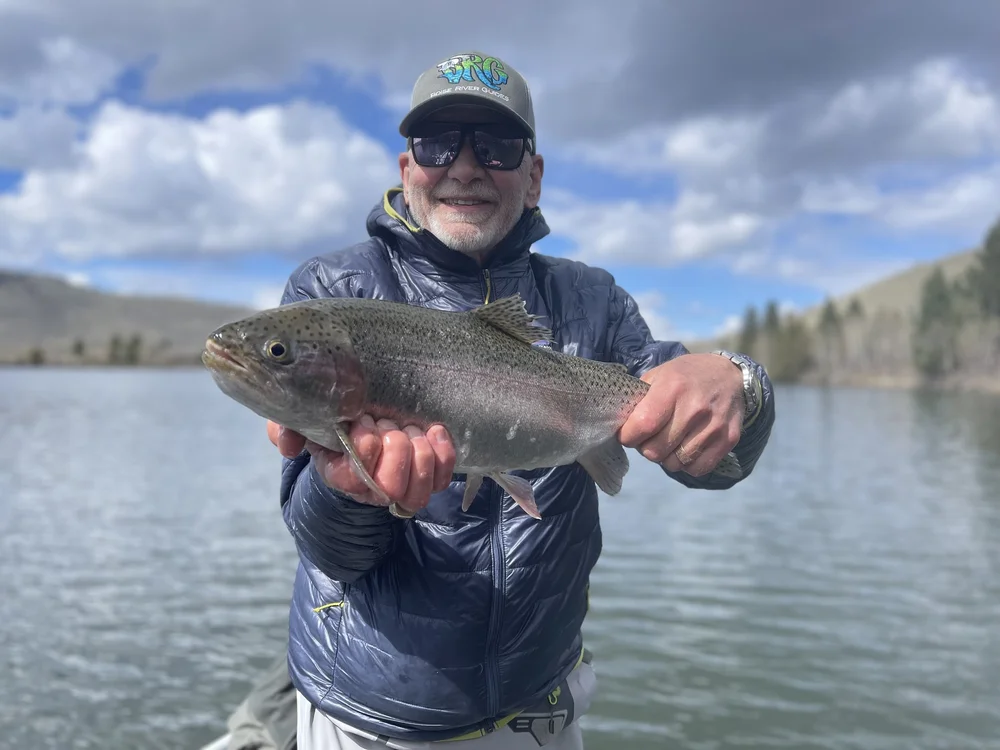 Angler releasing a rainbow trout from a Hubbard’s style private lake near Livingston Montana.