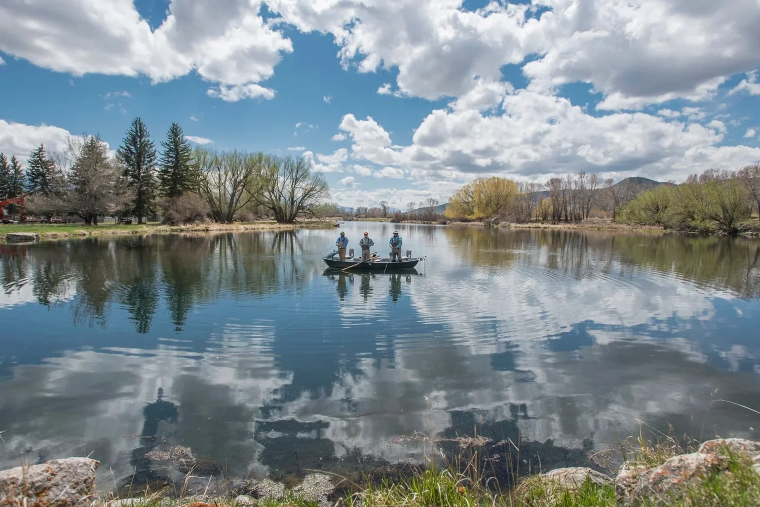 Two anglers on DePuy's Spring Creek with clouds reflected in the water