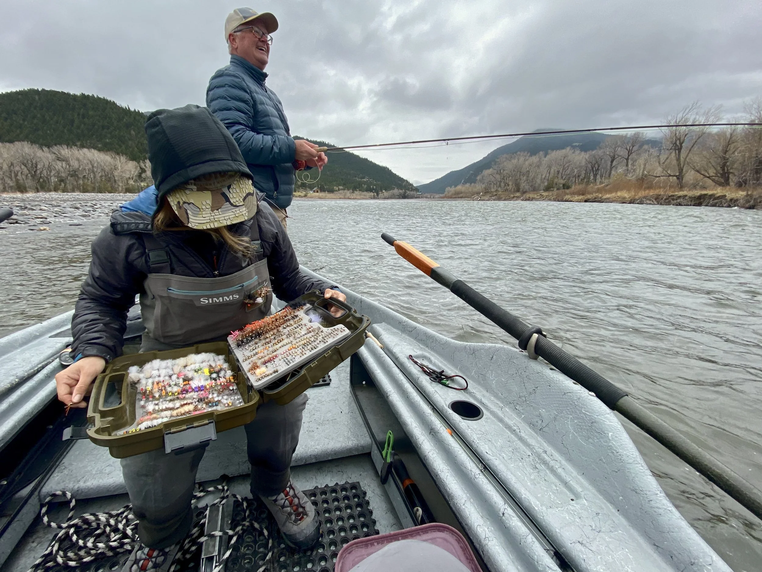 Fly fishing guide and guest on a drift boat on the Yellowstone River in Montana on a cloudy day”