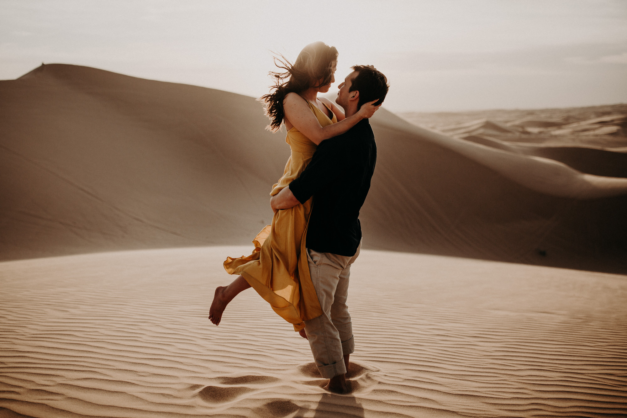 A man picks up his partner and embraces at the Glamis imperial sand dunes near Palm Springs.