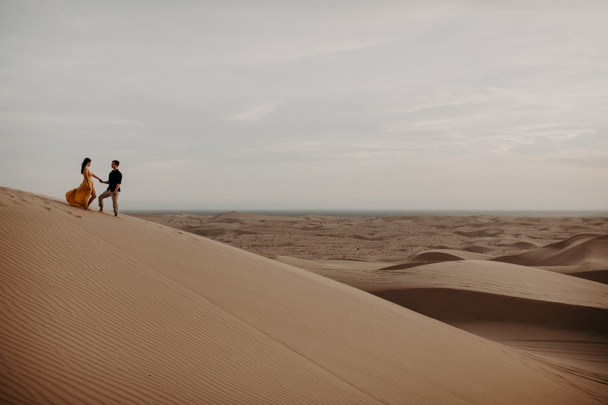 A couple standing at the top of a sand dune at the Glamis Imperial Sand Dunes near Palm Springs.
