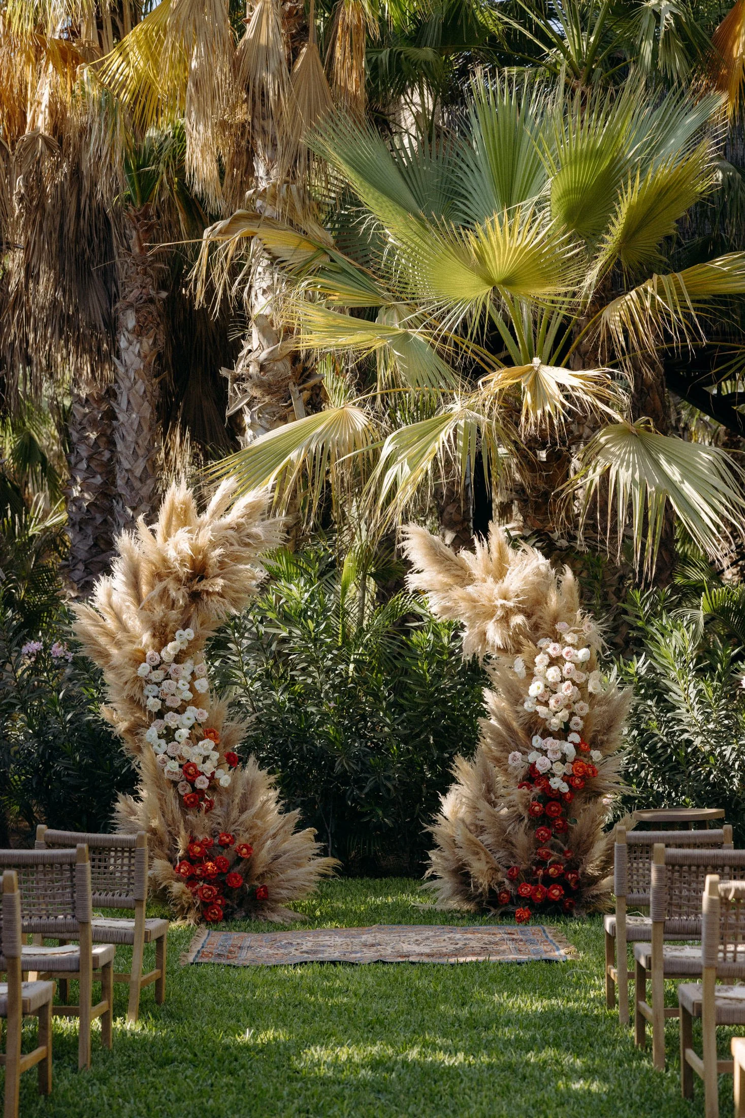 A view of the wedding ceremony space on lover's lawn with a floral arch in front of a forest of palm trees at acre resort in Cabo, Mexico
