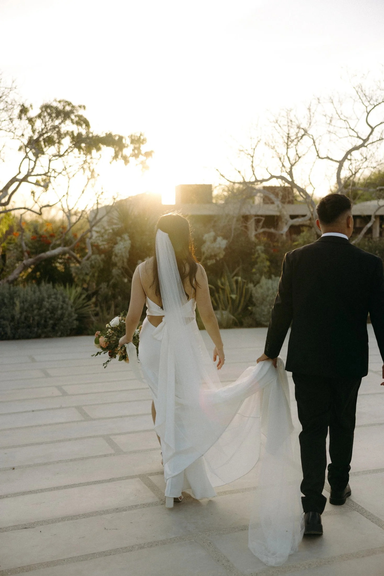 A wedding elopement couple walking into the sunset with a desert garden in the background at the los agaves area at acre resort in cabo, mexico