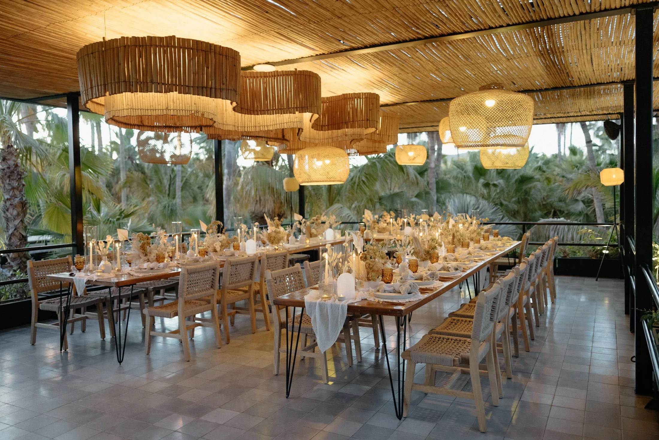 A wedding elopement reception set up of tables, chairs, and woven lights on the rooftop terrace at the acre resort in cabo, mexico