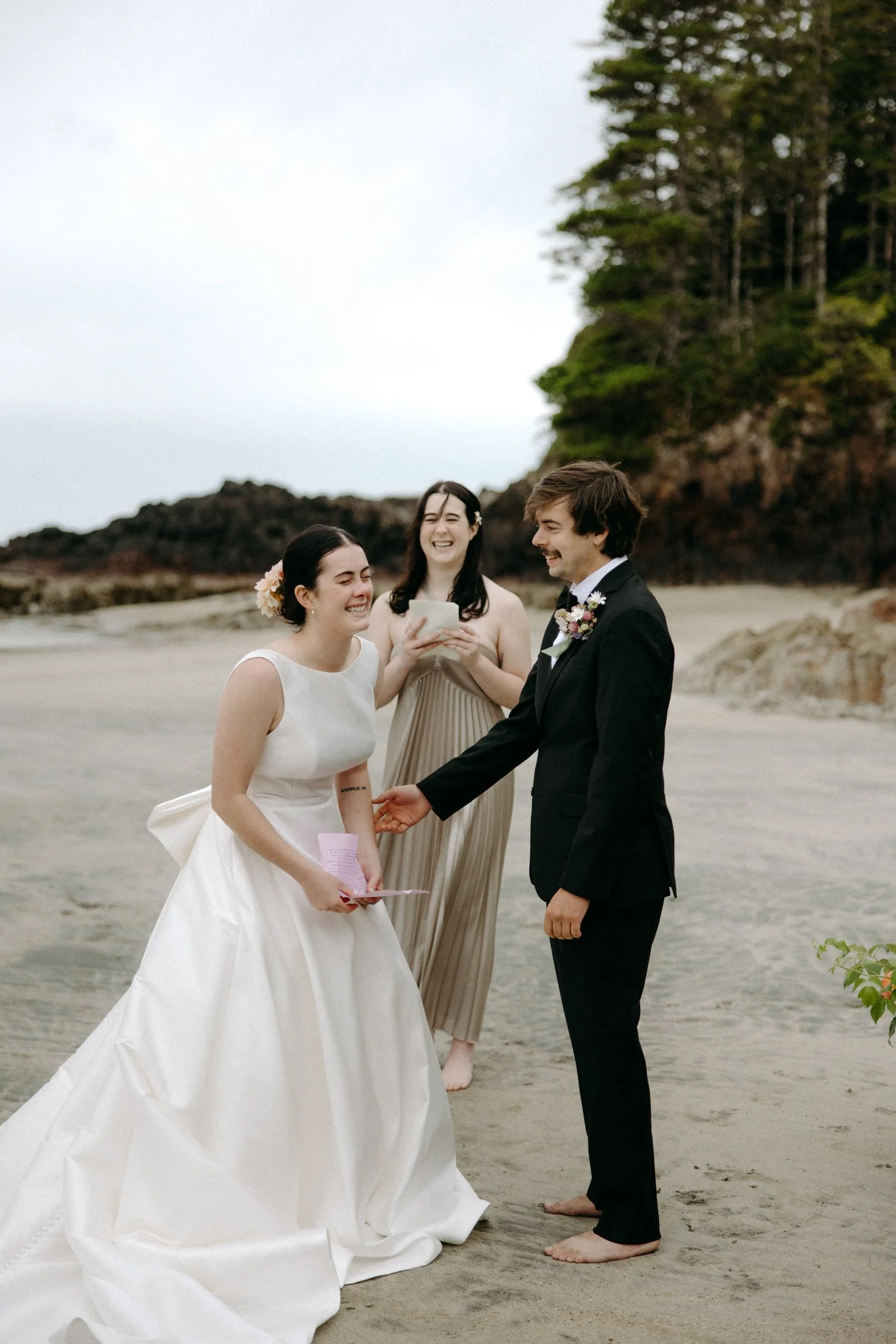 A couple says their vows at their elopement ceremony on the beach with the ocean and trees in the background at san josef bay in Cape Scott Provincial Park