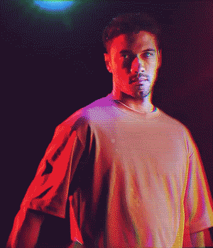 Person posing under colorful lighting with a confident expression, creating a neon-like effect.