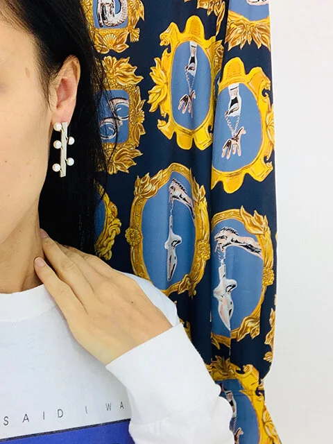  Ligia Dias, Protect me (2), 2019, earrings, silver, Akoya japanese pearls. Courtesy Ligia Dias   Contact for price   / Natacha Ramsay-Levi pour Chloé, Boyish shirt in crêpe de chine with a medallion print, Fall-Winter 2019. Private collection Geneva. Photo Jeanne-Salomé Rochat 
