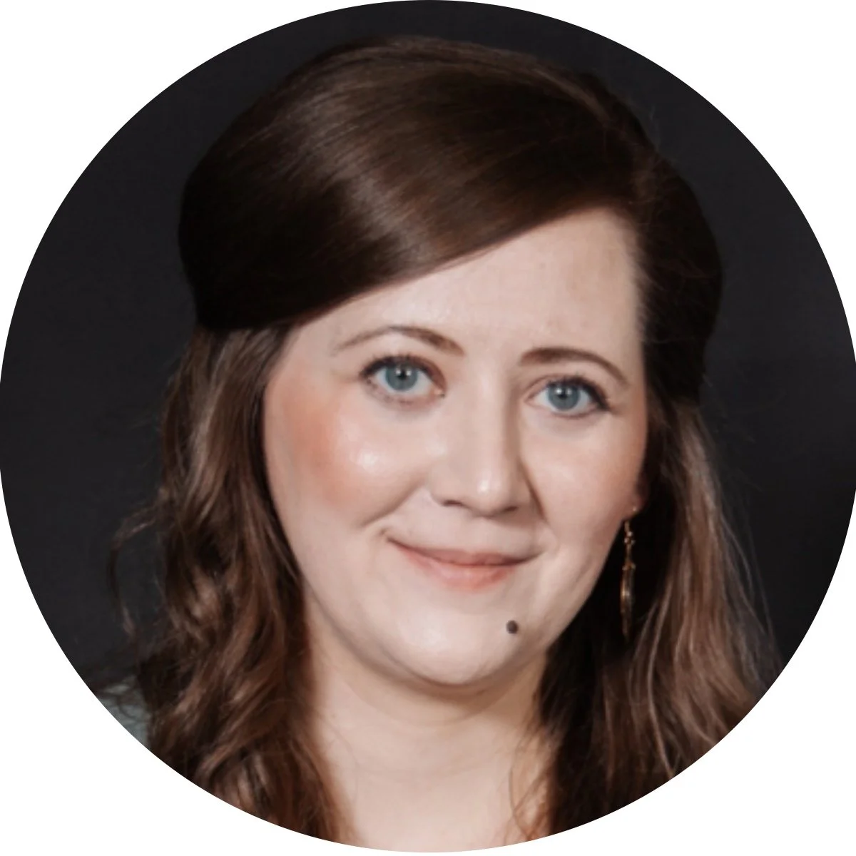 A woman with shoulder-length brown hair, blue eyes, wearing earrings and a neutral expression, against a black background.