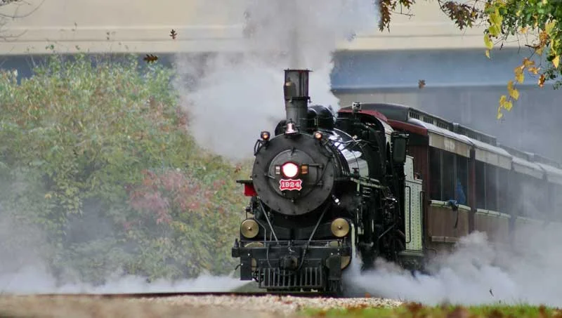 Test locomotive No. 1924 blasts up the 3% grade hauling a heavy train. The locomotive is being fired with 100% torrefied biomass fuel and is instrumented with test equipment to gauge firebed and smokebox temperatures.