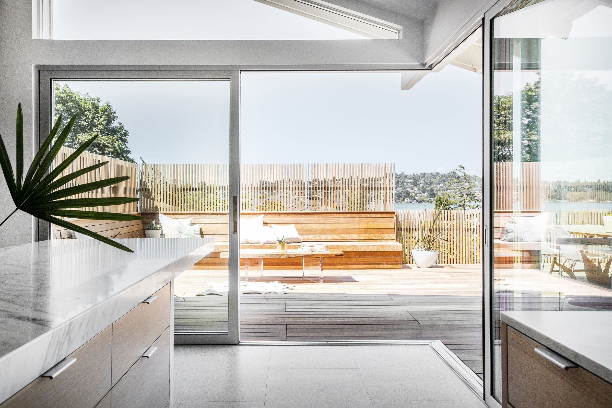 Aluminum open corner multi-slide doors opens onto the ipe terrace-- built in seating and wood slats screen the neighboring houses and frame the water view.