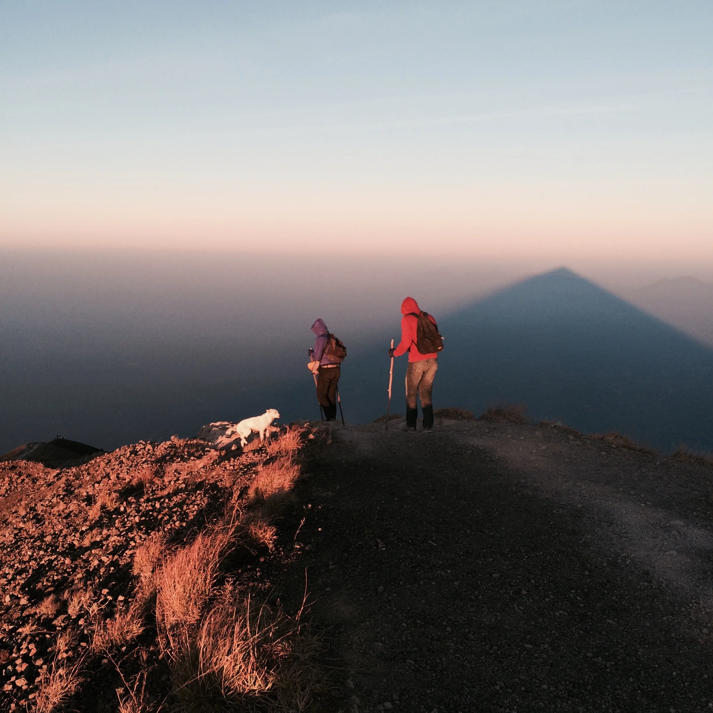 Hikers and the shadow of Mt Agung from the morning sun on clouds