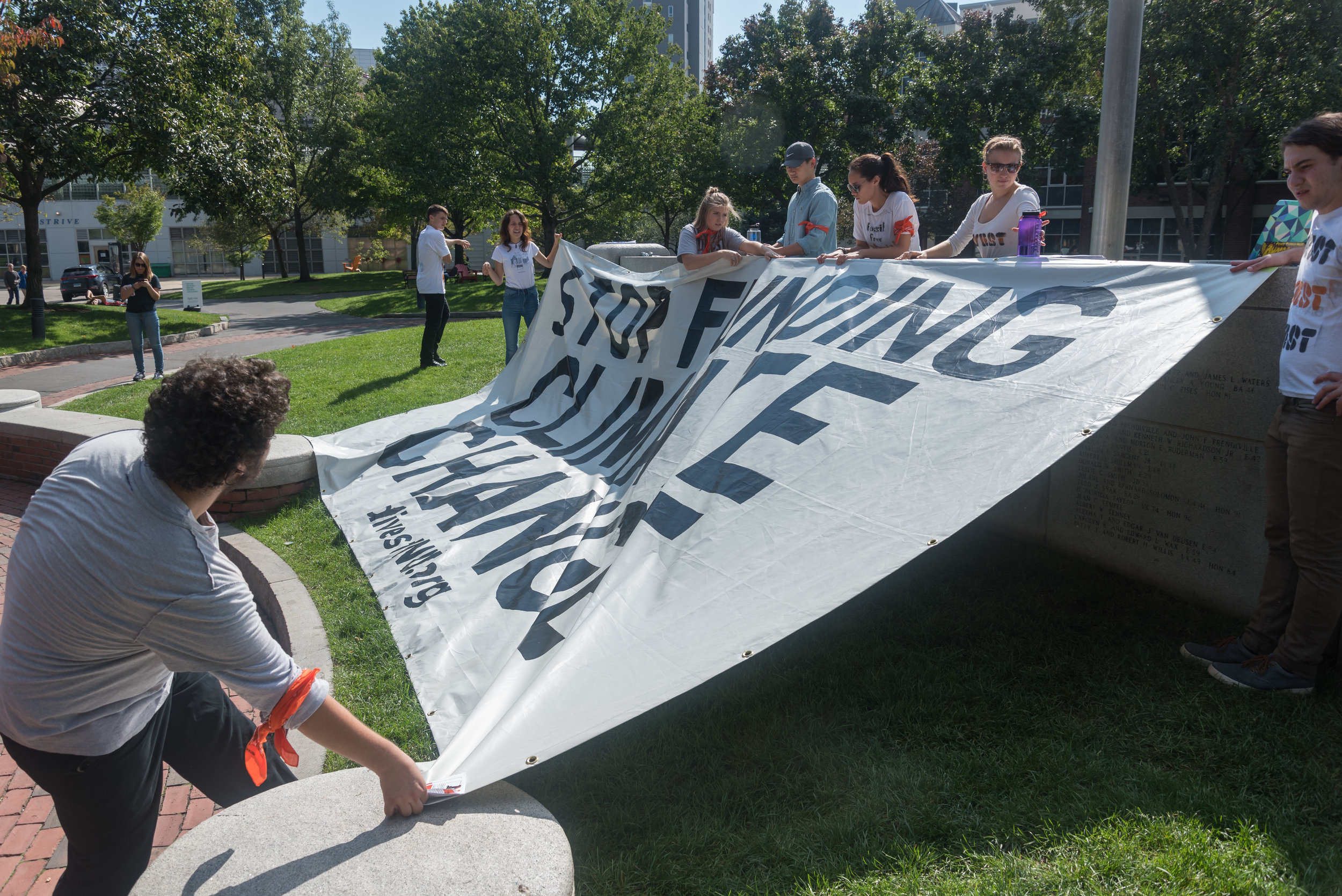  DivestNU member and Northeastern sophomore Ben Simonds-Malamud, left, pulls a large tarp over the front of Centennial on Monday, Oct. 3. The sign reads "Stop Funding Climate Change."  "[Northeastern] basically said as long as we're peaceful and nonv