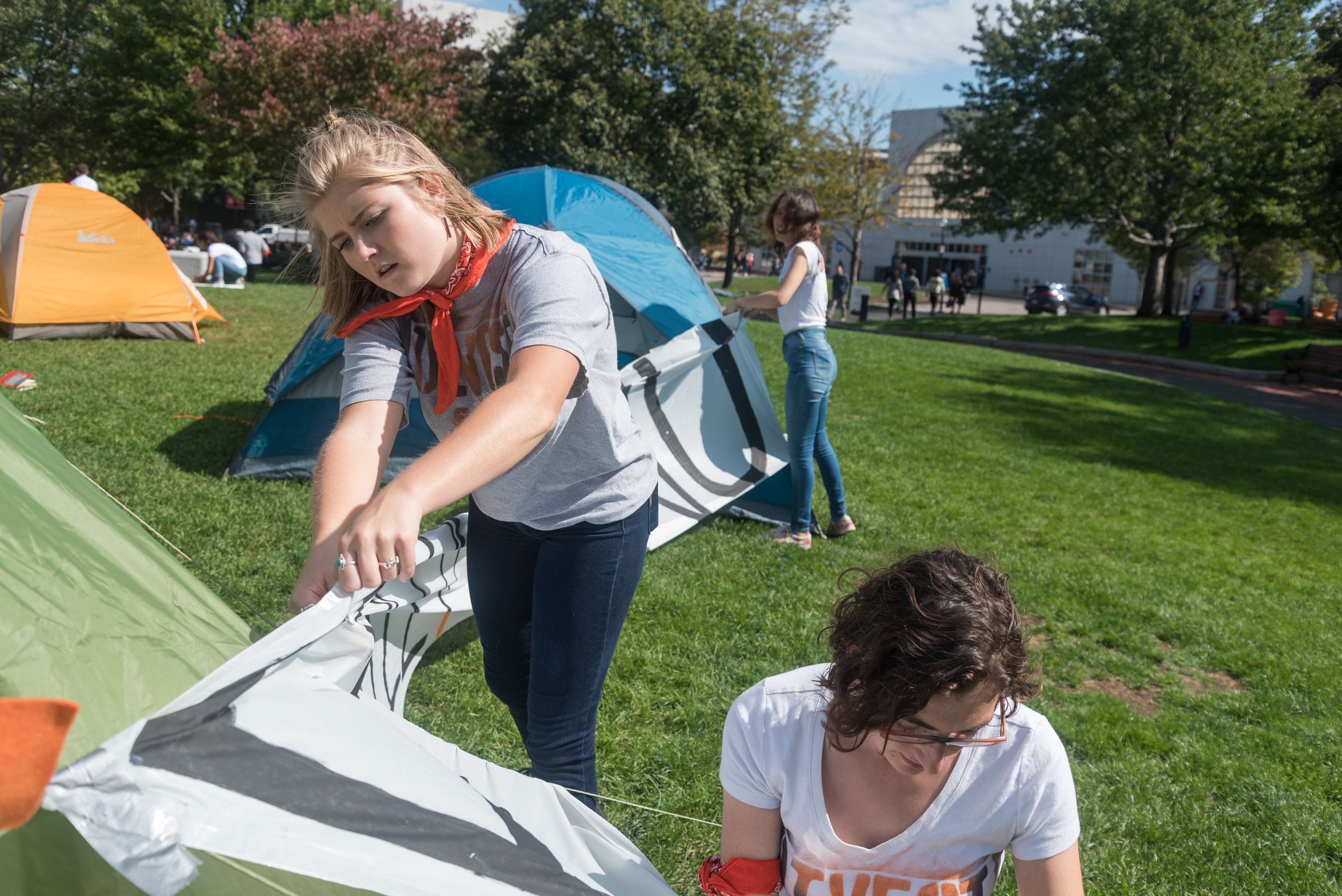  DivestNU members Savannah Kinzer, left, and Alissa Zimmer, right, tape a sign to tents during a protest on Centennial Common on Monday, Oct. 3.&nbsp;  "I've been part of [DivestNu] since my freshman year. I think over the years seeing how this issue