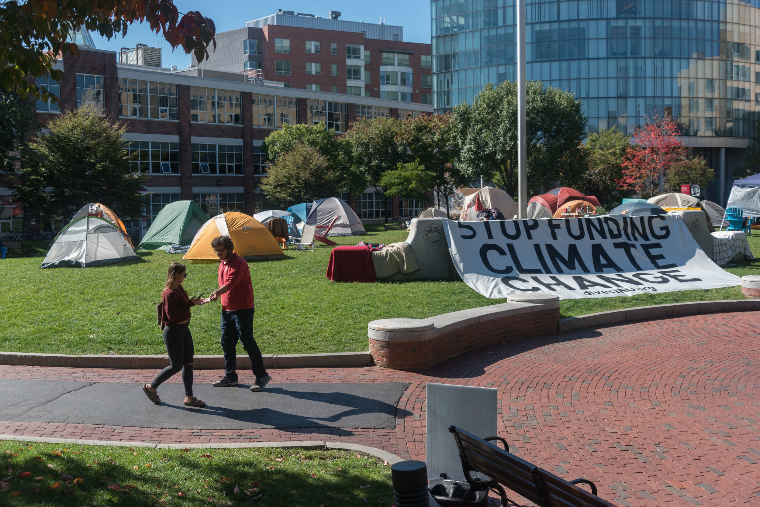  DivestNU member Ben Simonds-Malamud hands out flyers during the group's almost two-week stay on Centennial Common on Tuesday, Oct. 11, 2016. 