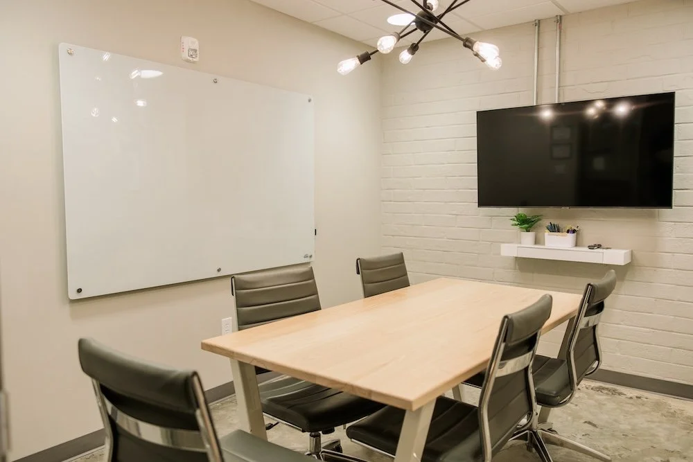 Meeting room with table,  five chairs, smartv, and whiteboard