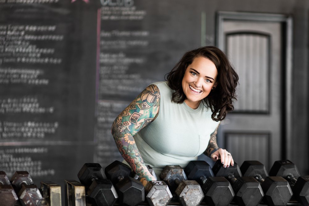 okc oklahoma norman commercial photography woman with brown hair with tattoos picking up a weight in the gym headshots branding photography