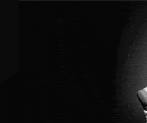 A black and white photograph of a person riding a bicycle in a narrow, dimly lit alleyway, Fiverr logo.