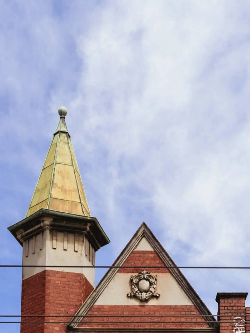 Industrial elegance meets Victorian detail.
This red-brick gable and copper-tipped spire are hallmarks of Victorian Free Gothic architecture &mdash; a style that mixed medieval inspiration with Melbourne&rsquo;s boom-era confidence. The ornate crest,