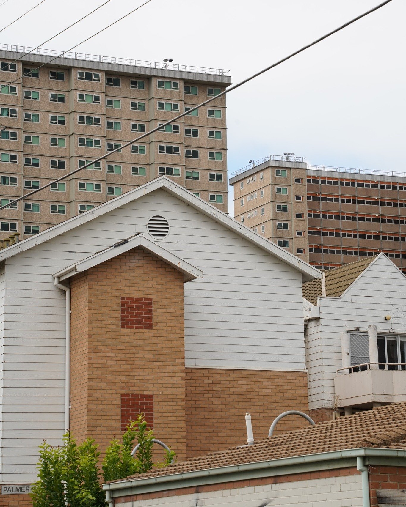 A small Collingwood backstreet moment, easy to miss if you&rsquo;re not looking. Brick and weatherboard pressed up against each other, towers hovering in the background. Wires criss-cross the sky, pigeons claim their perch and the street hums softly 