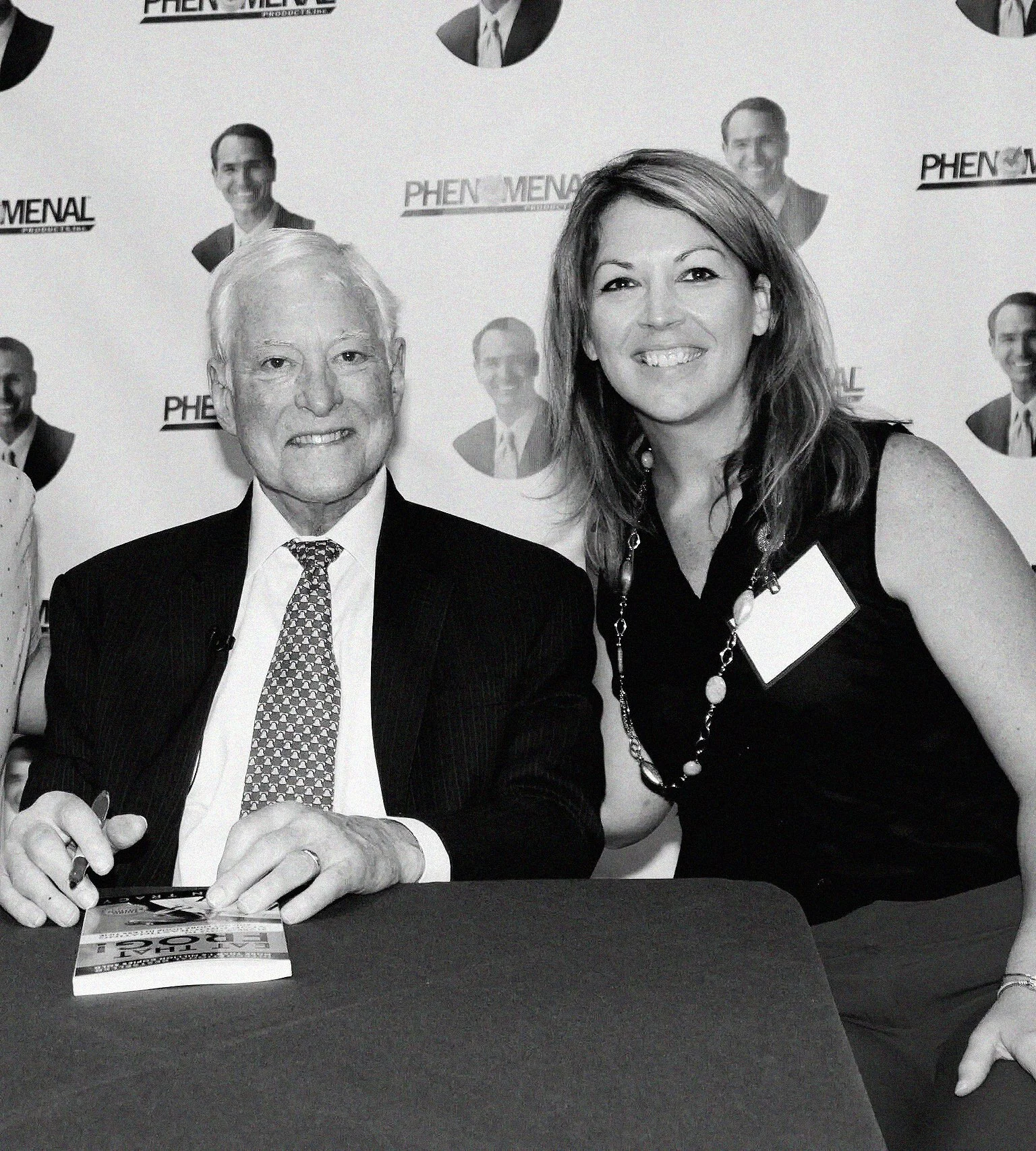 a woman at a book signing party of an old man standing next to him