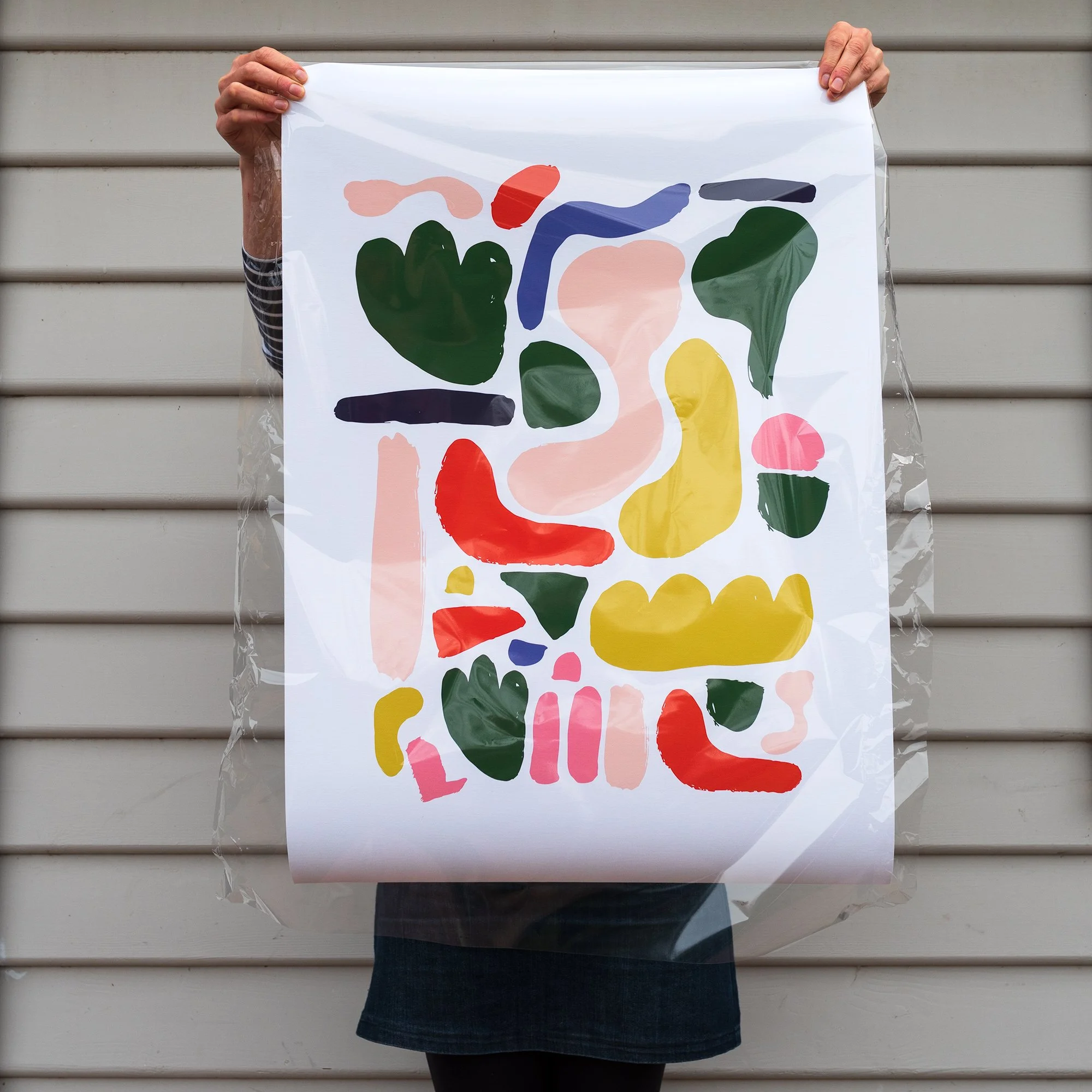 Photo of a large colourful art print being held up by a person