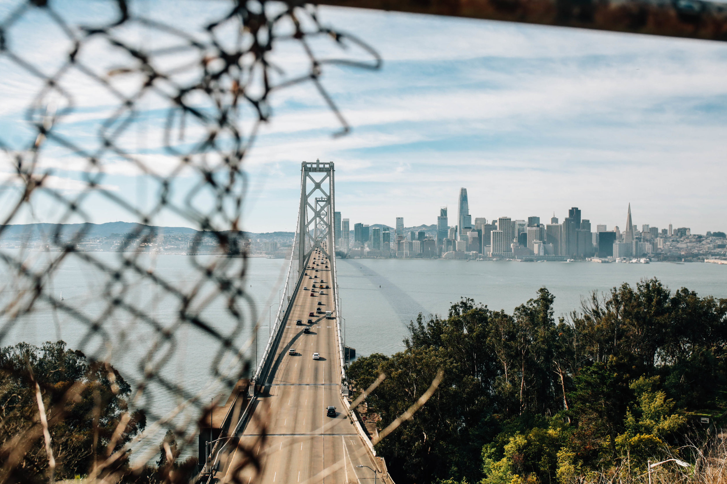 The San Francisco skyline view from the bridge with an out-of-focus chain-link fence in the foreground