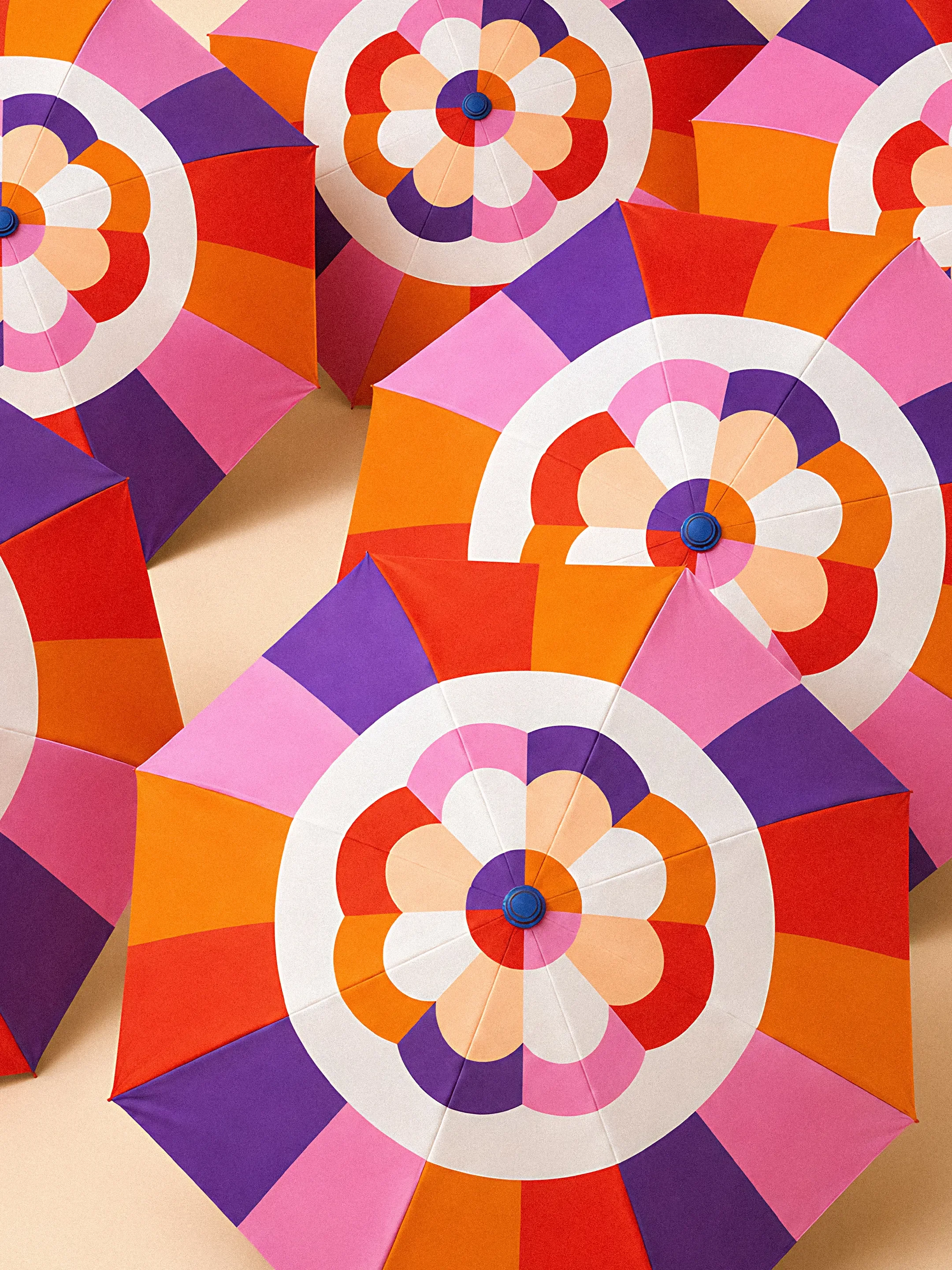 Sombrillas de colores en tonos rosa, naranja, púrpura y blanco con patrones geométricos.