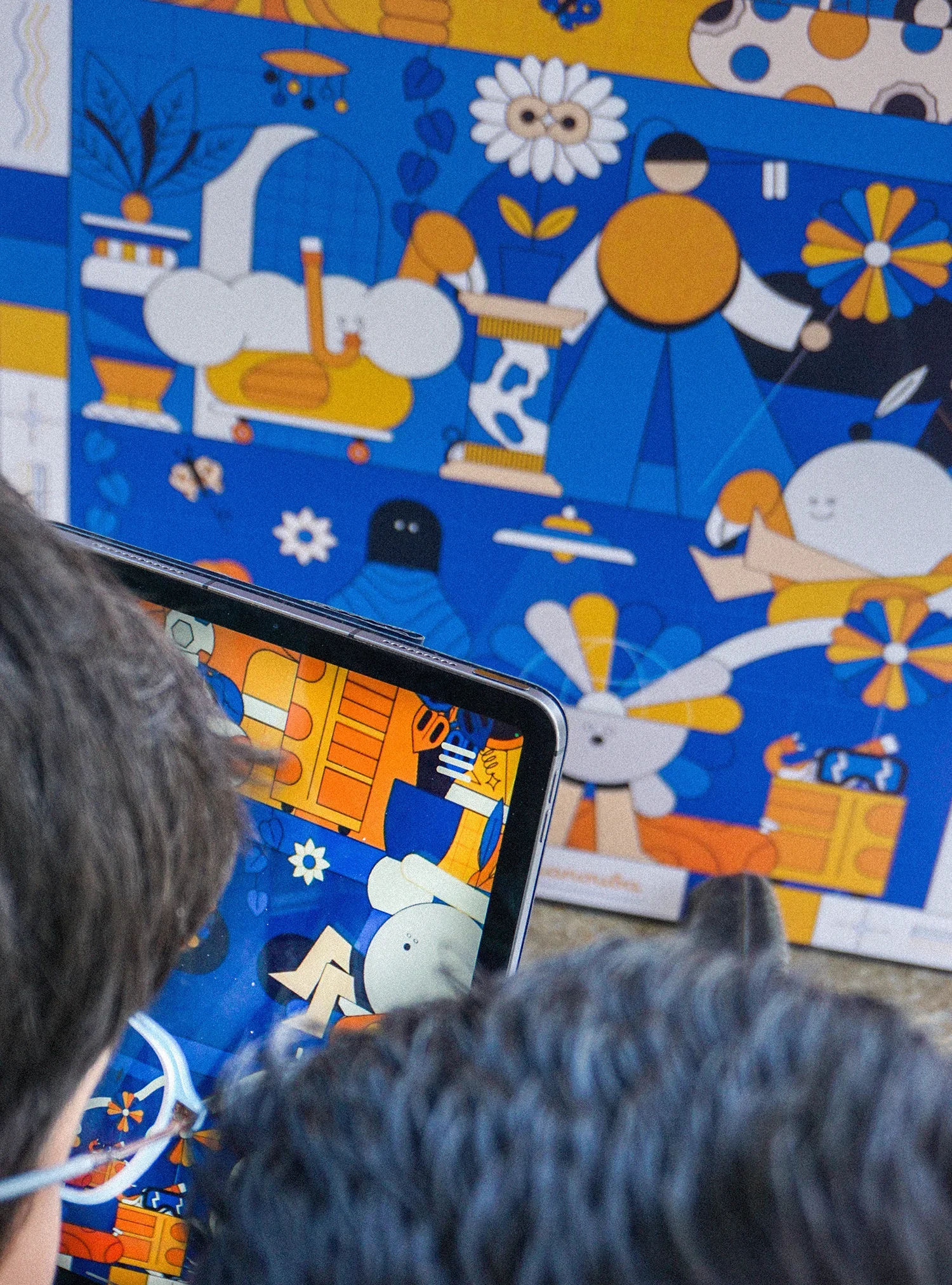 Une personne regarde une tablette avec une illustration colorée devant un panneau ou une affiche similaire.