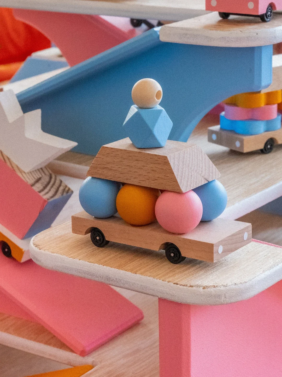 Jeu de construction en bois avec des formes géométriques colorées et des roulettes, formant une structure verticale.