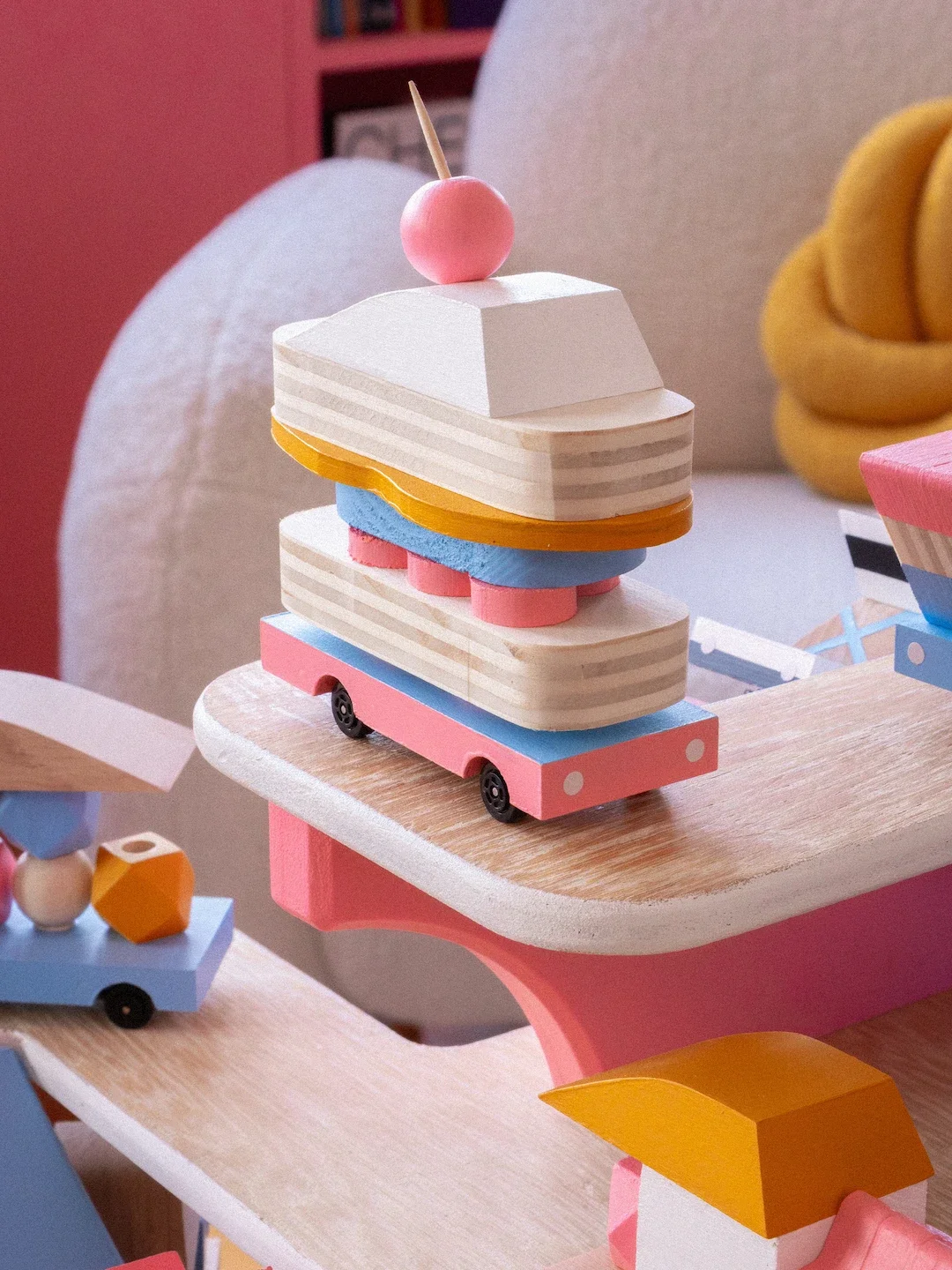 Palets en bois peints en couleurs pastel, assemblés pour former une création artistique ou un jouet, avec un fond de chambre décorée.