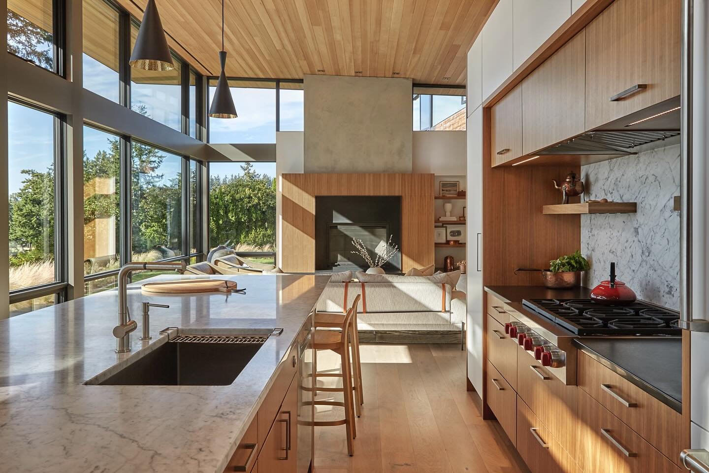 Oriented towards the breathtaking view of Bellingham Bay, the kitchen at our #MCT_GlasswingHouse features warm quarter sawn walnut cabinets complimented by the surrounding Carrara slab, absolute black granite countertop, and a subtly concealed integr