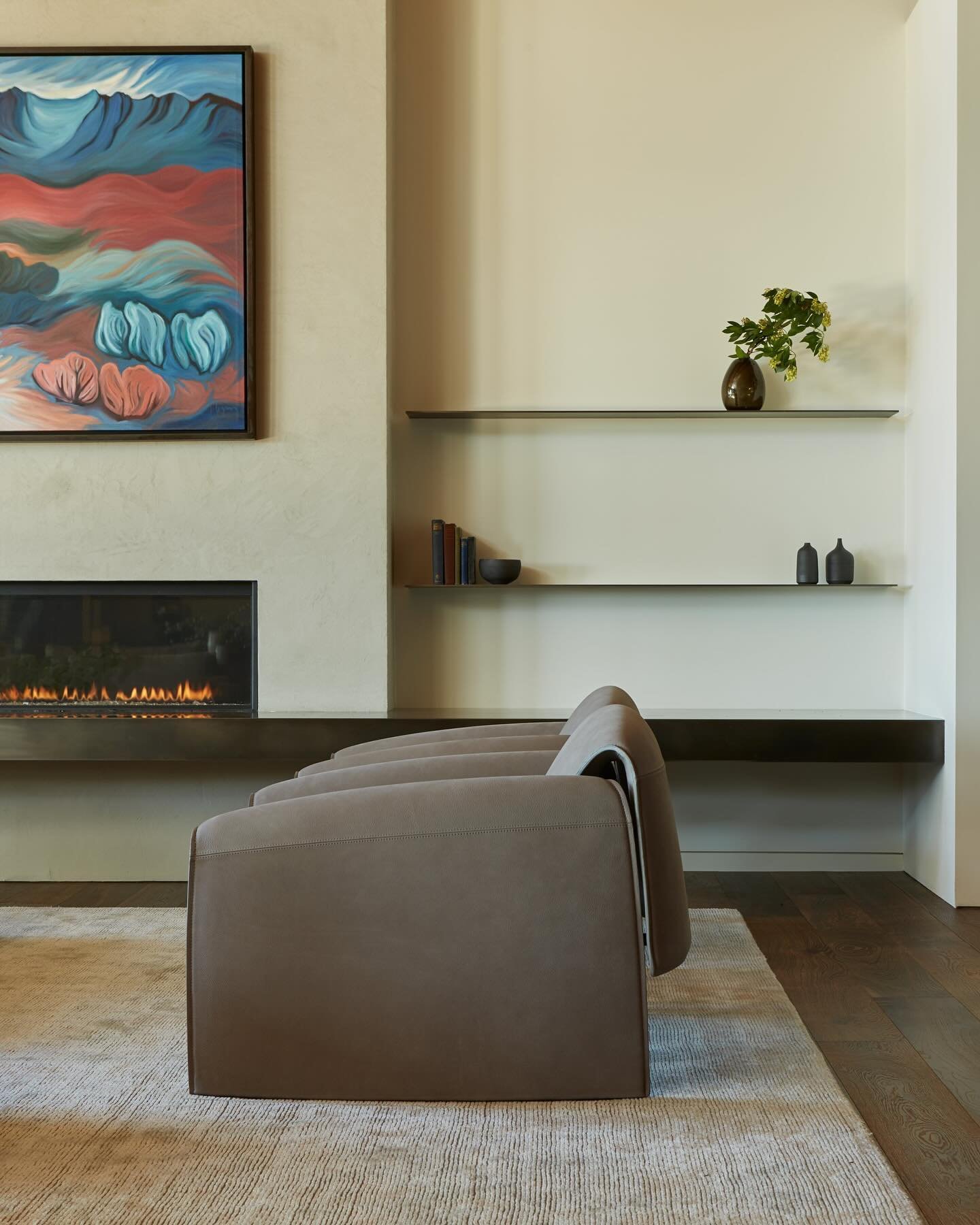 The sculptural armchairs in the living room at our #MCT_CorvusHouse&nbsp;were curated to provide a unique silhouette seen from all angles. Paired with sleek floating steel shelves and hearth, the custom artwork creates a beautiful focal point over th