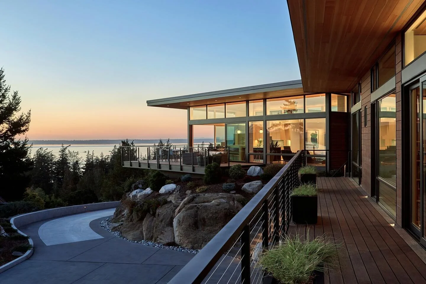 Swipe to experience the expansive water views from our #MCT_EyrieHouse - softly aglow at dusk and bathed in sunshine by day. Despite the challenging steep site, the design managed to strategically place the home atop the rocky hillside, creating a sp