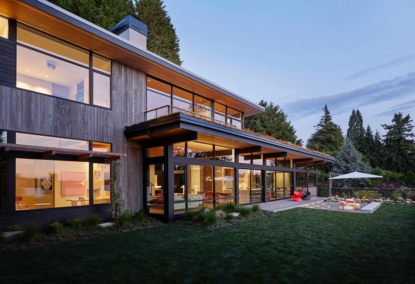 A lush green roof overhang at our #MCT_PerchHouse takes a simple covered patio roof line and enhances the expansive lake views from the primary suite, framing the perspective with a natural landscaping accent and creating a strengthened connection to
