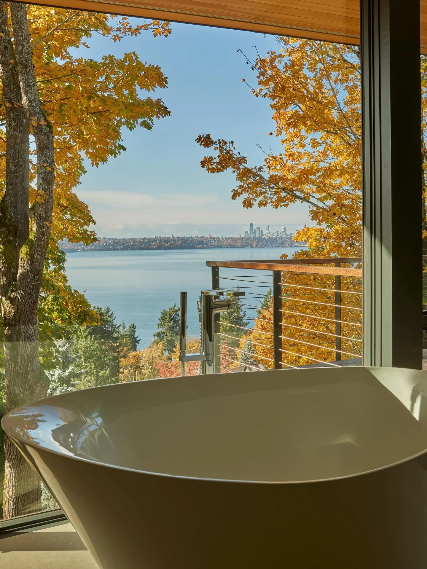 A tranquil oasis tucked amongst the trees, the Primary Suite at our #MCT_CorvusHouse seamlessly connects the bedroom and bathroom through oversized pocketing doors to maximize the expansive views of Lake Washington beyond. The Seattle skyline, seen f
