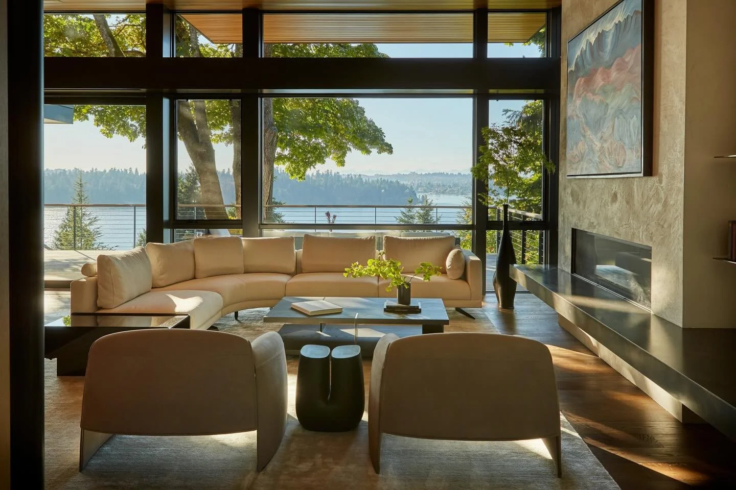 Designed as an open-concept gathering space, the great room at our #MCT_CorvusHouse captures sweeping views of Lake Washington through expansive floor-to-ceiling glazing. Vibrant custom artwork by @jillloganartisttodossantos deepens the connection be