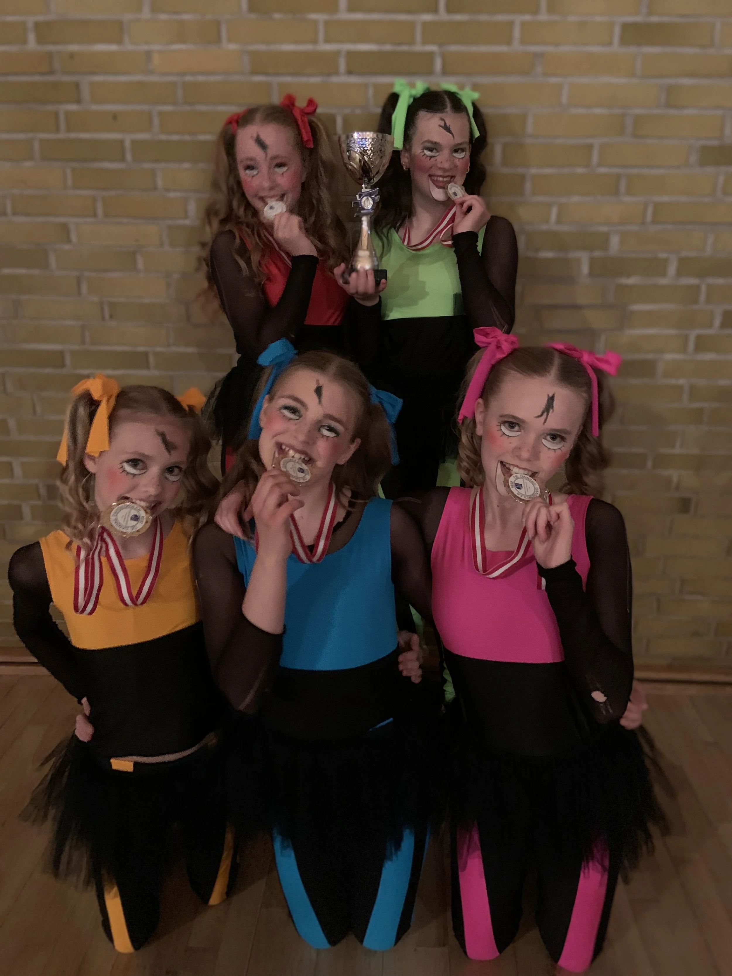Fem dansere fra Dansefeber poserer som danmarksmestre i showdance med guldmedaljer og pokal