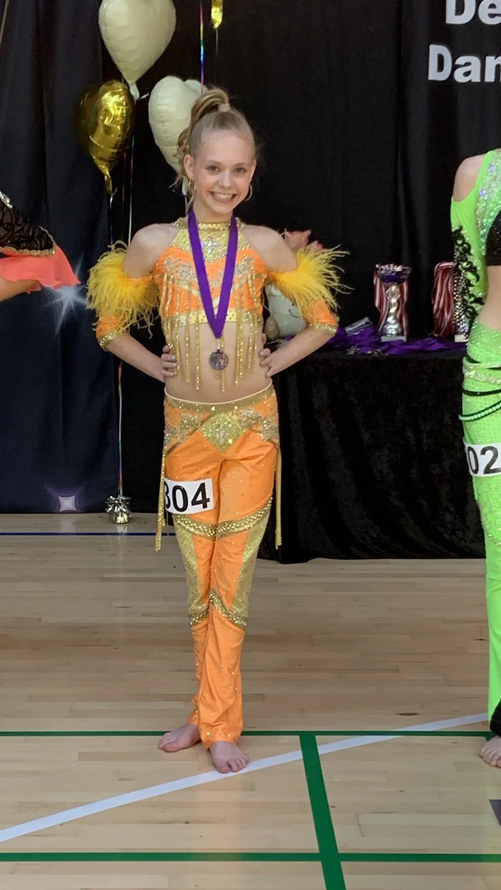 Discodanser fra Dansefeber i Viby J med medalje ved dansekonkurrence, i orange og guld dragt