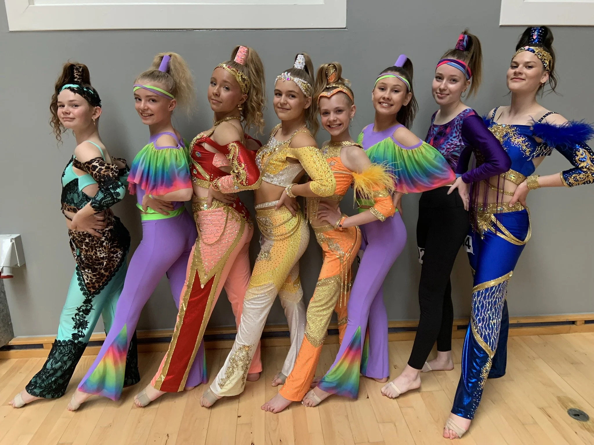 Otte dansere fra Dansefeber i Viby J i farverige konkurrencekostumer, studieportræt