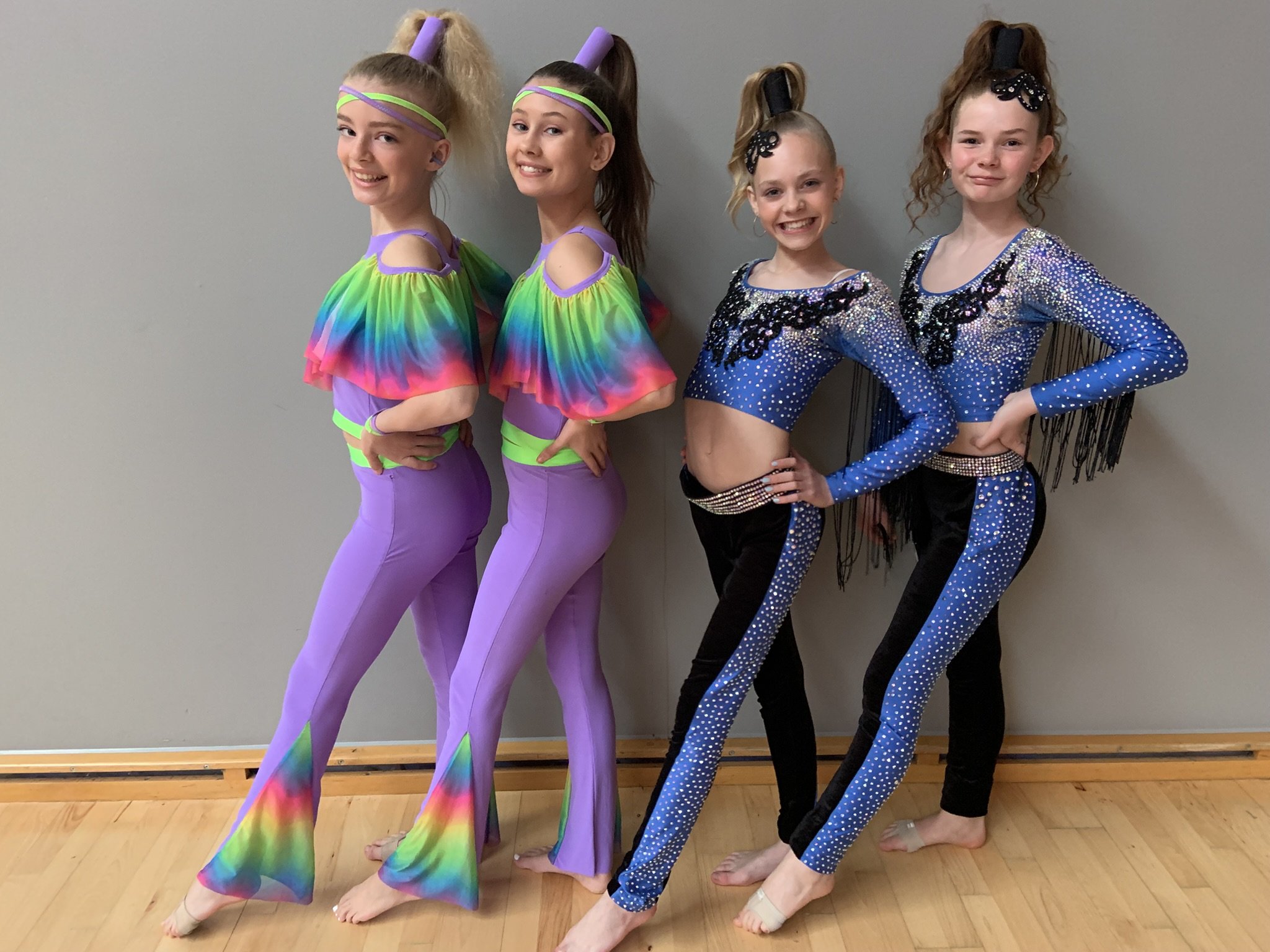 Fire dansere fra Dansefeber i Viby J i lilla og blå glitterkostumer, studieportræt