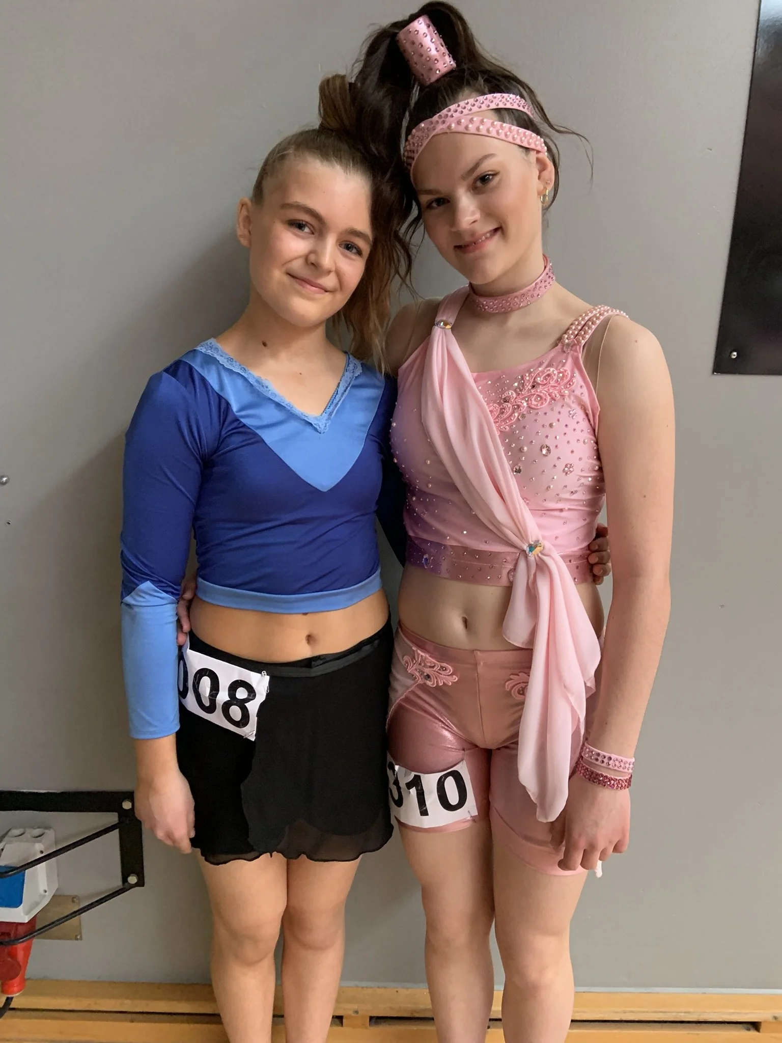 To dansere fra Dansefeber i Viby J i studieportræt ved dansekonkurrence, i blå og pink dragter