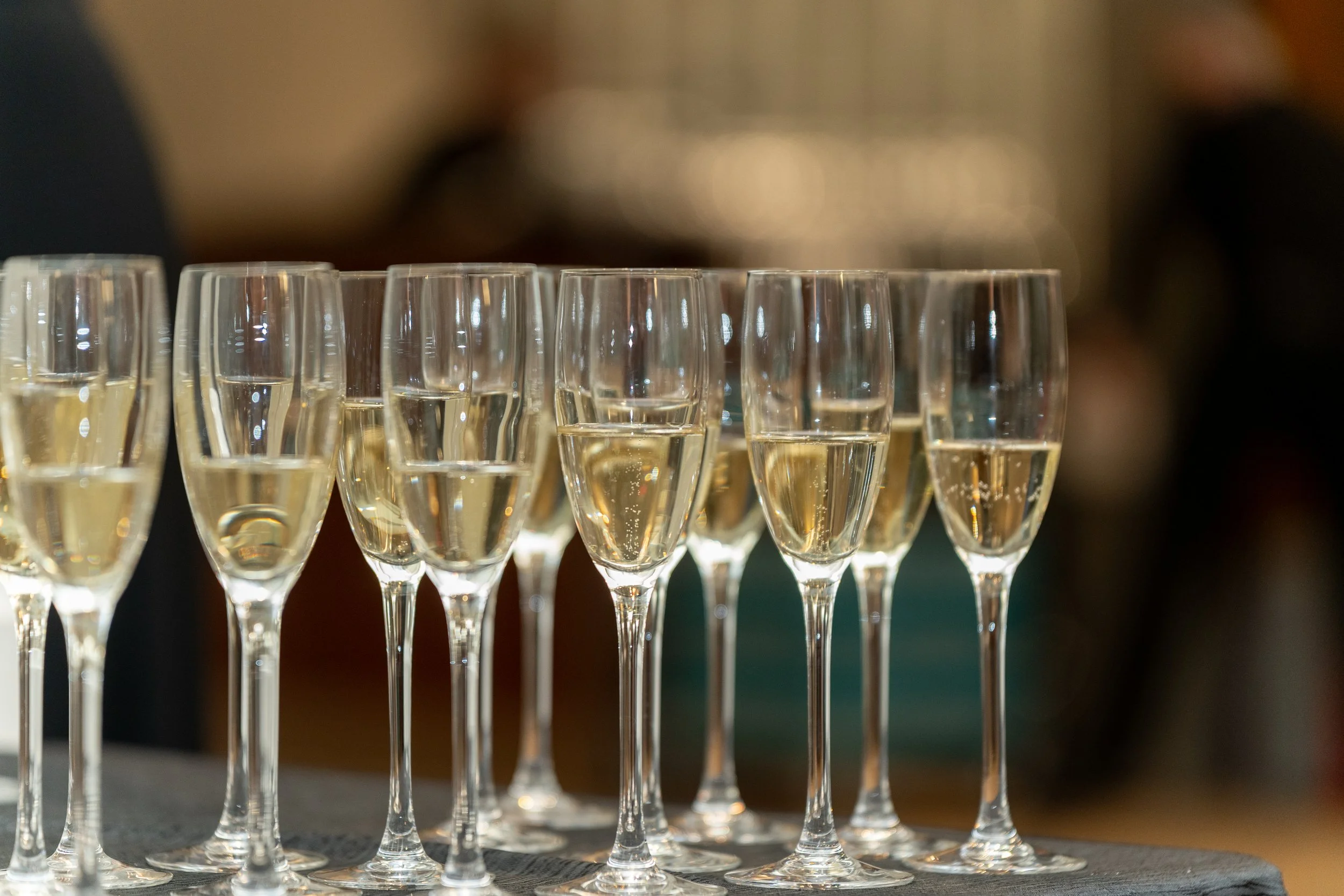 Multiple champagne glasses filled with sparkling wine arranged on a table.