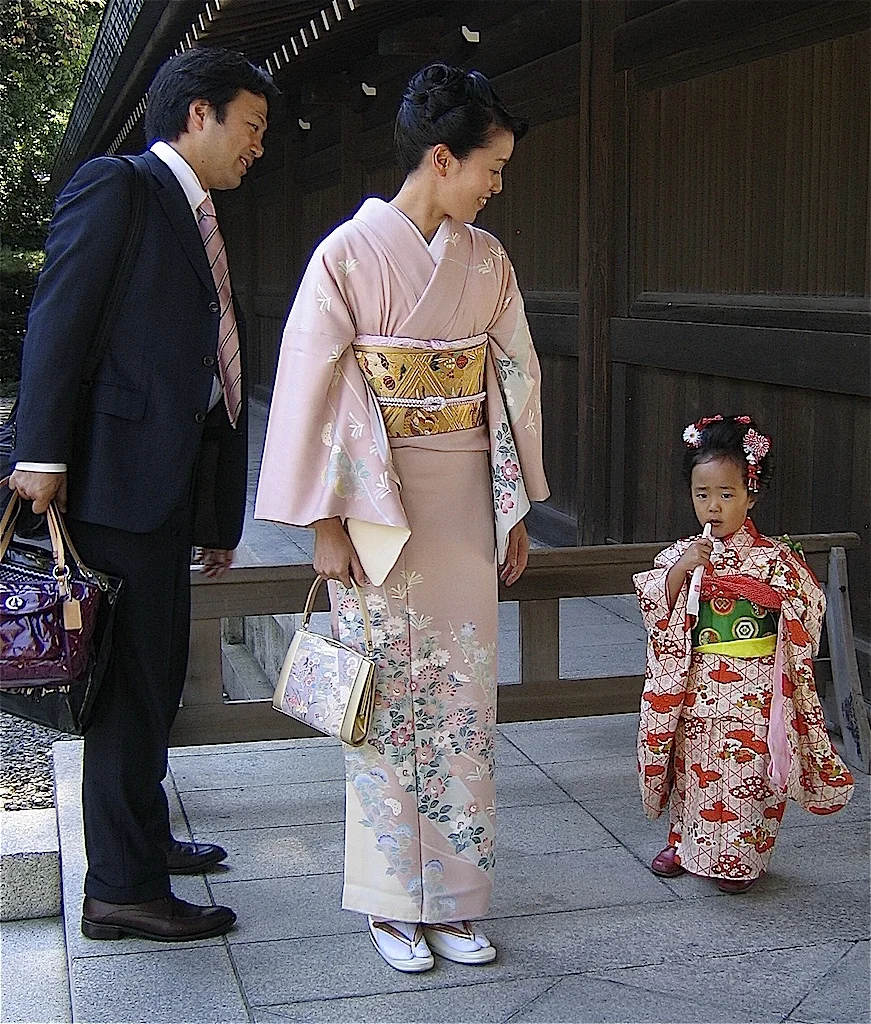   13-12  This photo exemplifies the rules for both gender and age. The father is dressed in a dark suit; the mother's formal kimono is less colorful than that of her young daughter.  