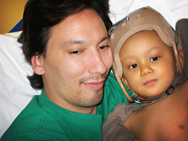 "Hunter and Zen snuggling is his bed at the hospital. The helmet is to keep his head safe when he was low on platelets. A lil' knock or cut on the head would like to be prevented, and he was having to learn how to walk all over again because of the way the chemo broke down is lil' body. So tumbles happened often." / Photo Courtesy Lenore Davis
