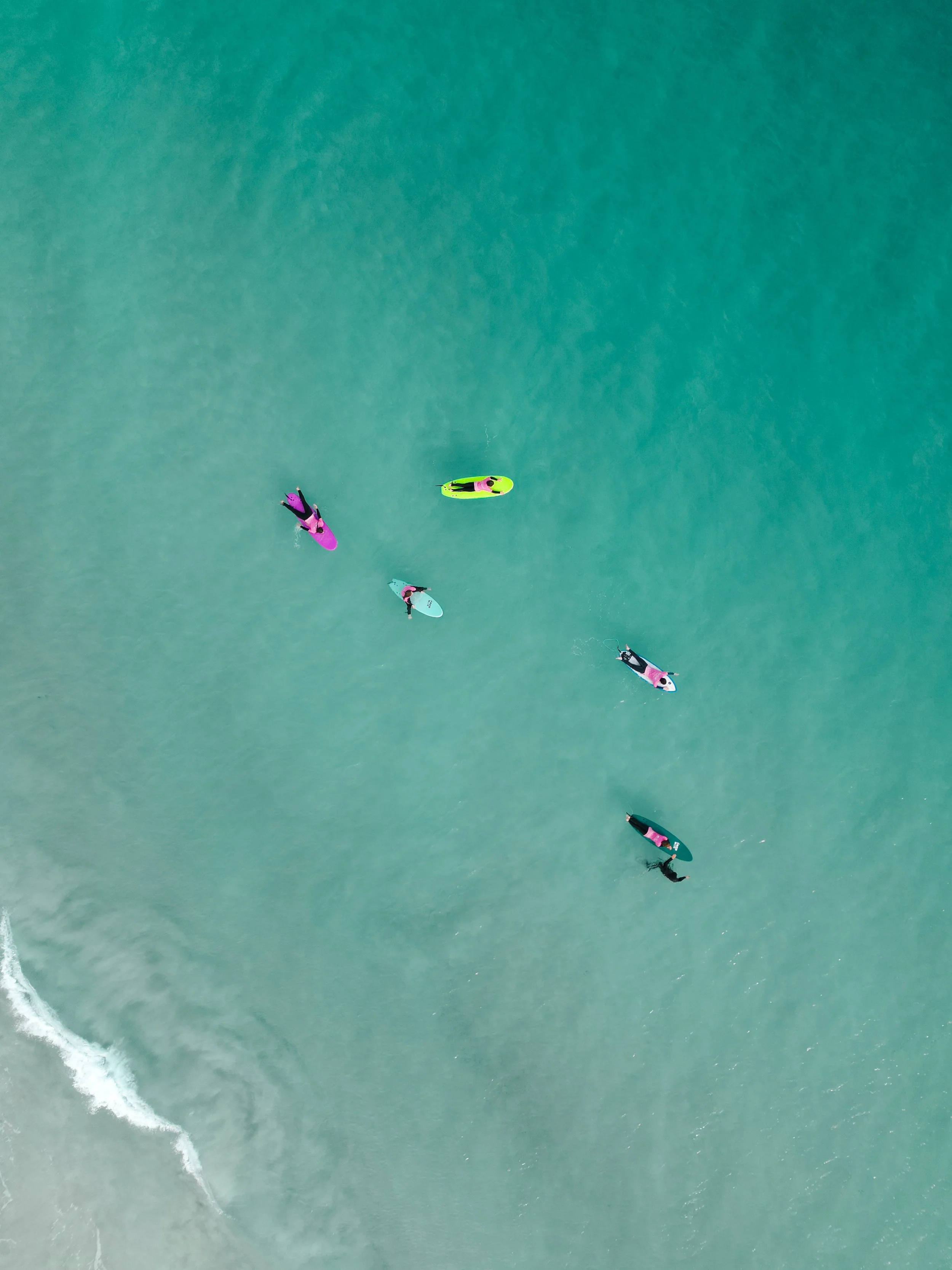Aerial view of beginner surfers on soft-top boards during a group surf lesson in Perth, Western Australia