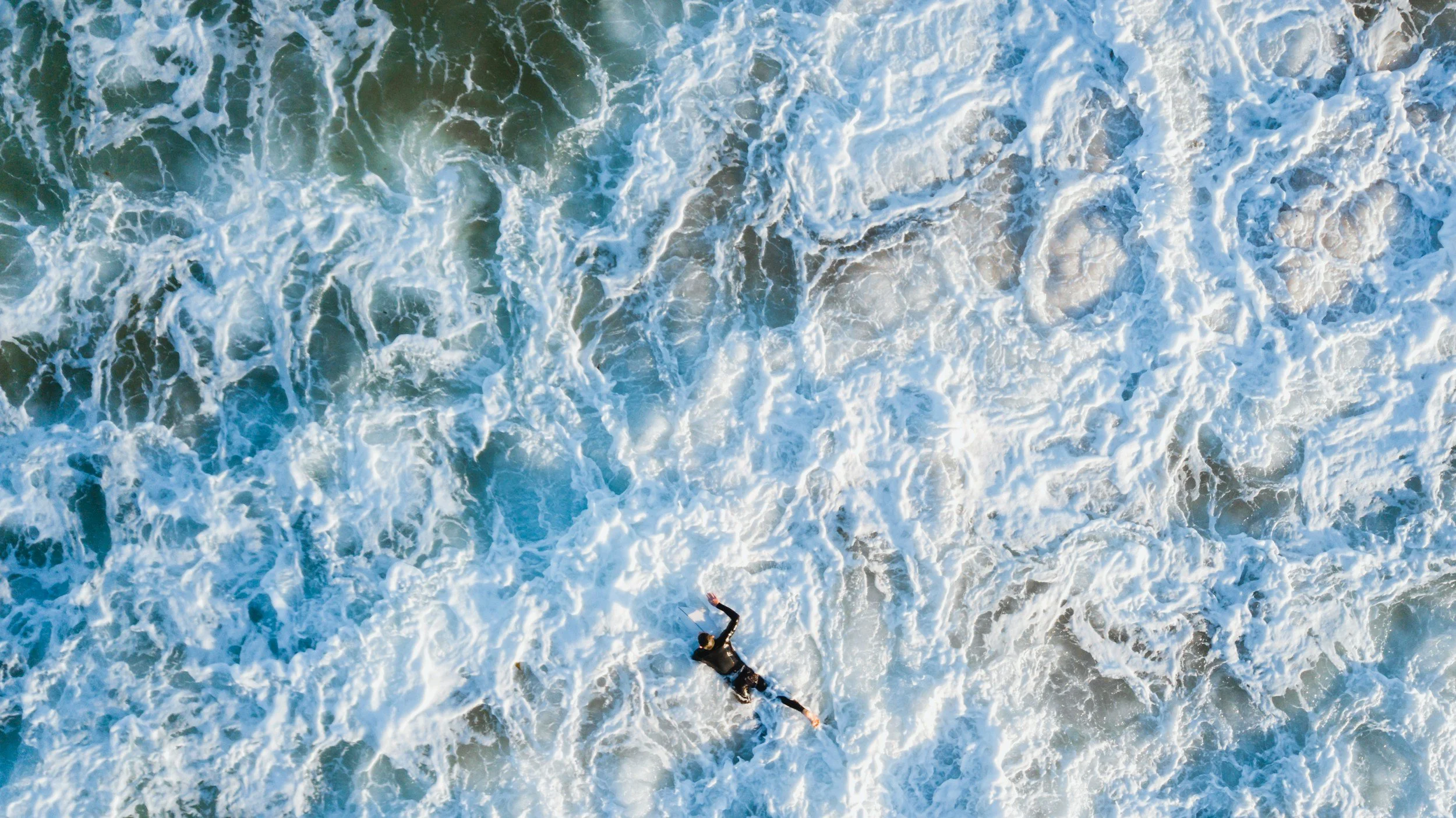 Surfer struggling against whitewash while learning to surf alone