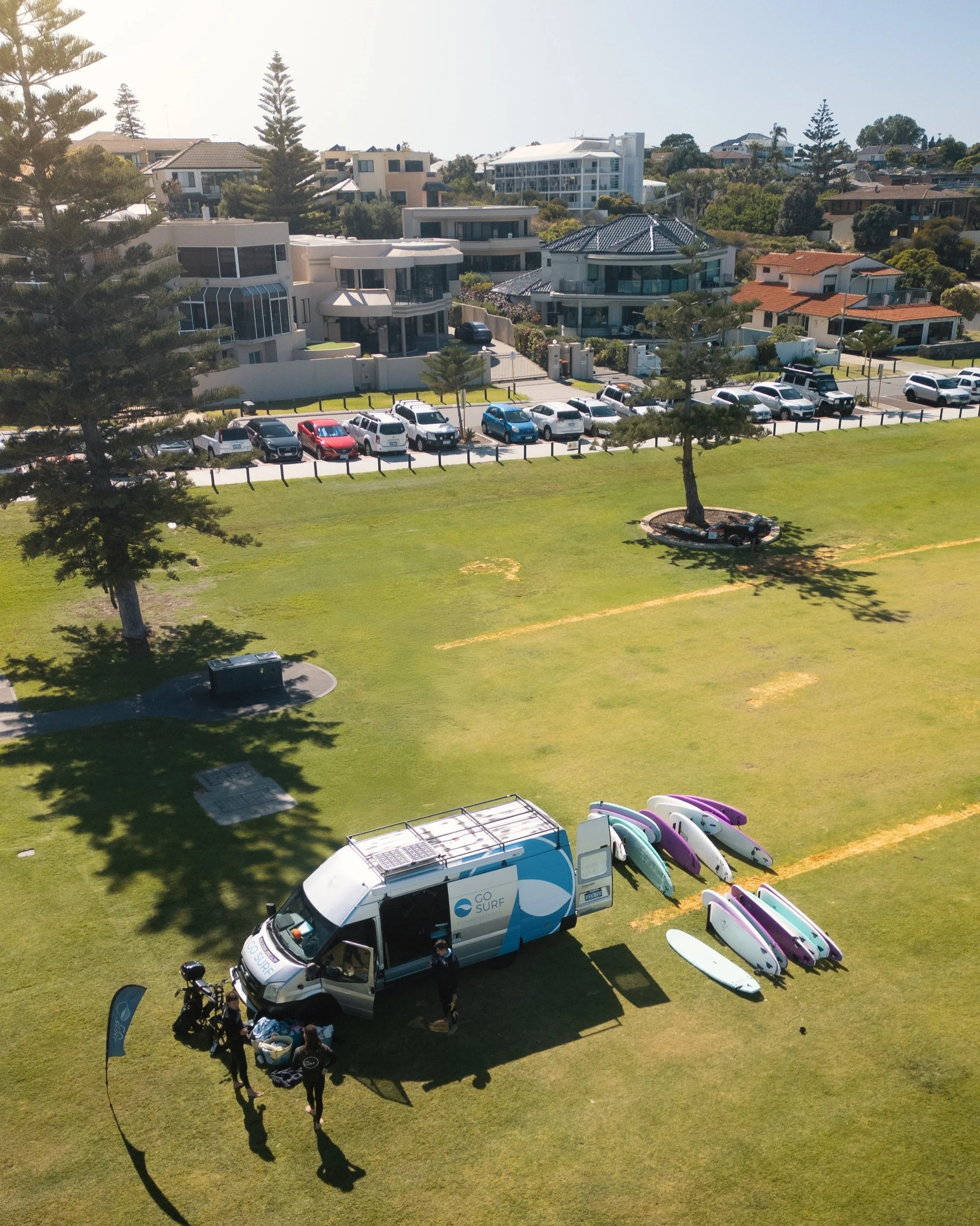 A parked van in a grassy field surrounded by surfboards, suggesting a day of surfing and outdoor adventure.A parked van in a grassy field surrounded by surfboards, suggesting a day of surfing and outdoor adventure.