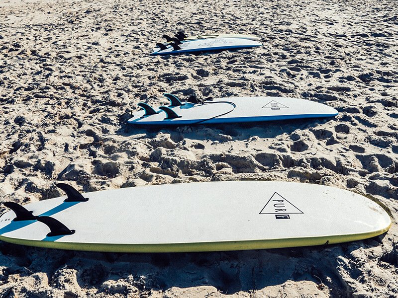 Surfboards lined up on the sand, ready to be rented by learner surfers