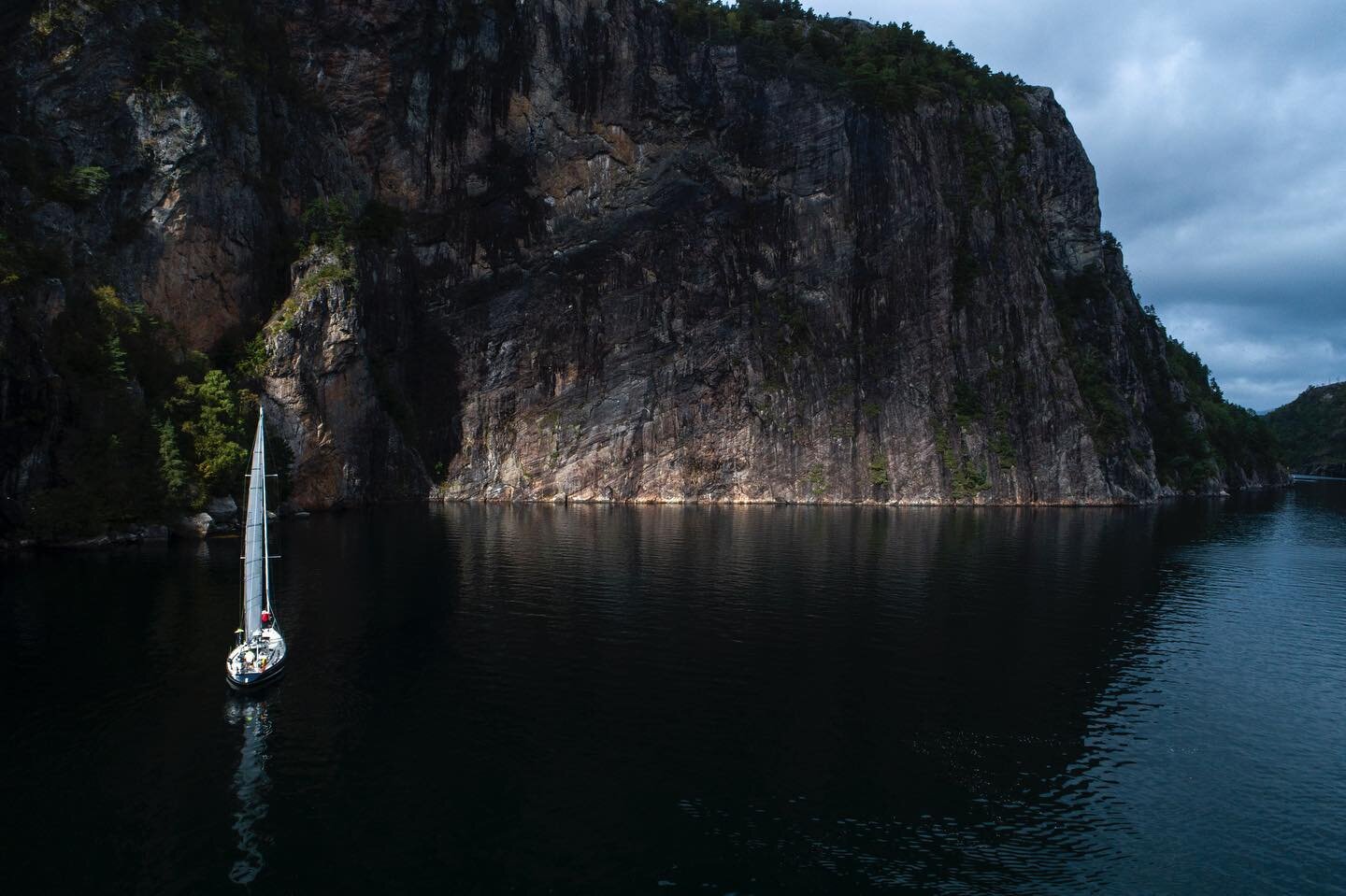 A sliver of light gives glow to the steep wall. Cutting in close in deep northern fjords :) 
Isbjorn @59northsailing 

#isbjornsailing #norway #norge #seil #seilnorge #fjord #fjords #fjordsofnorway #sail #sailing #sailinglife #utno #utinaturen #norve